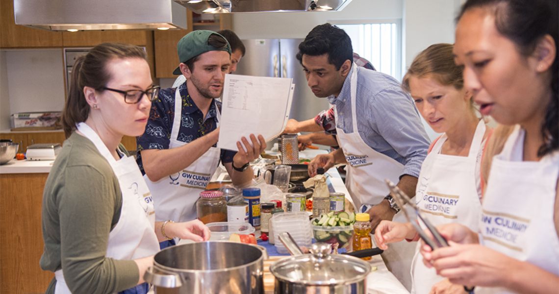 med students cooking in aprons in a kitchen