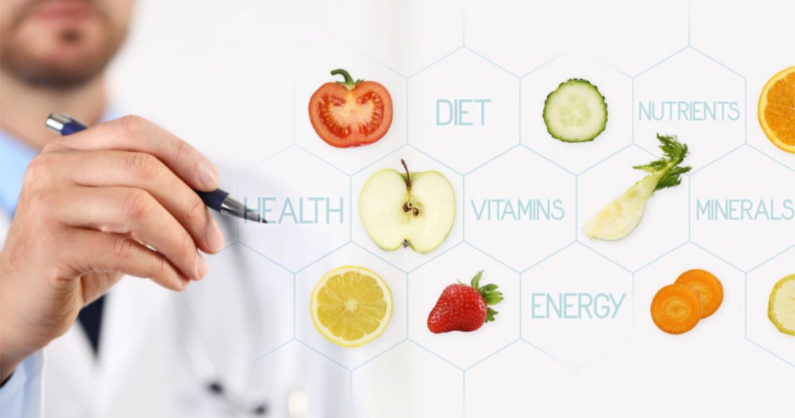 Doctor pointing with a pen to a wall of fruits and vegetables with nutrition-related words